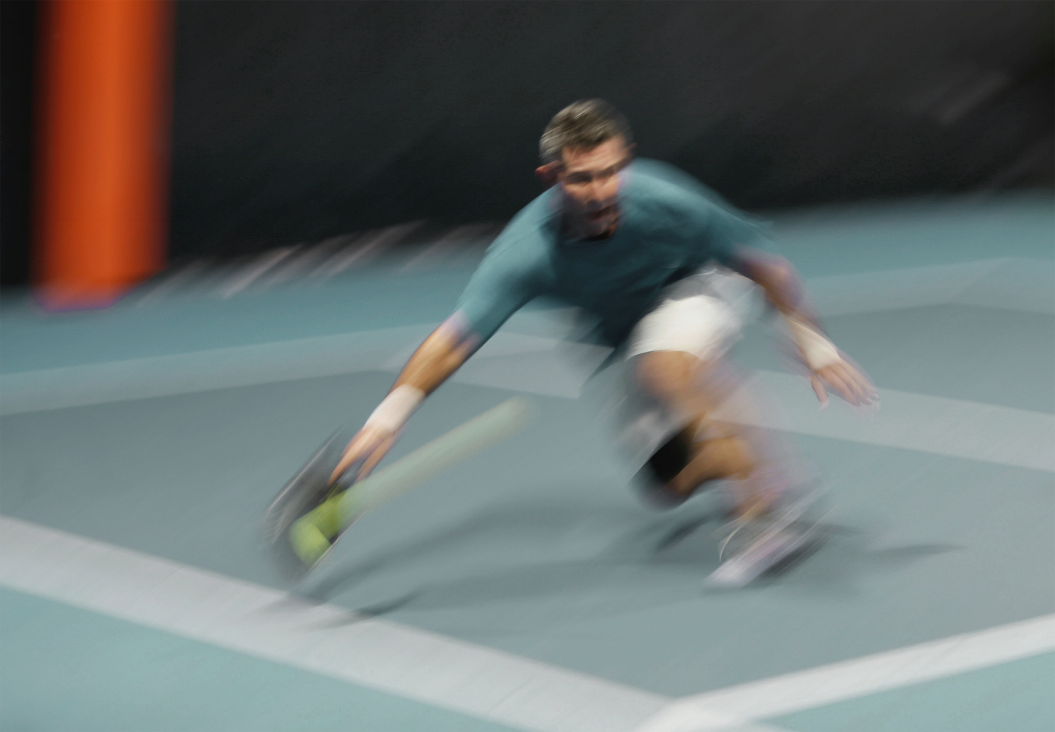 Man reaching out with tennis racket to hit tennis ball.