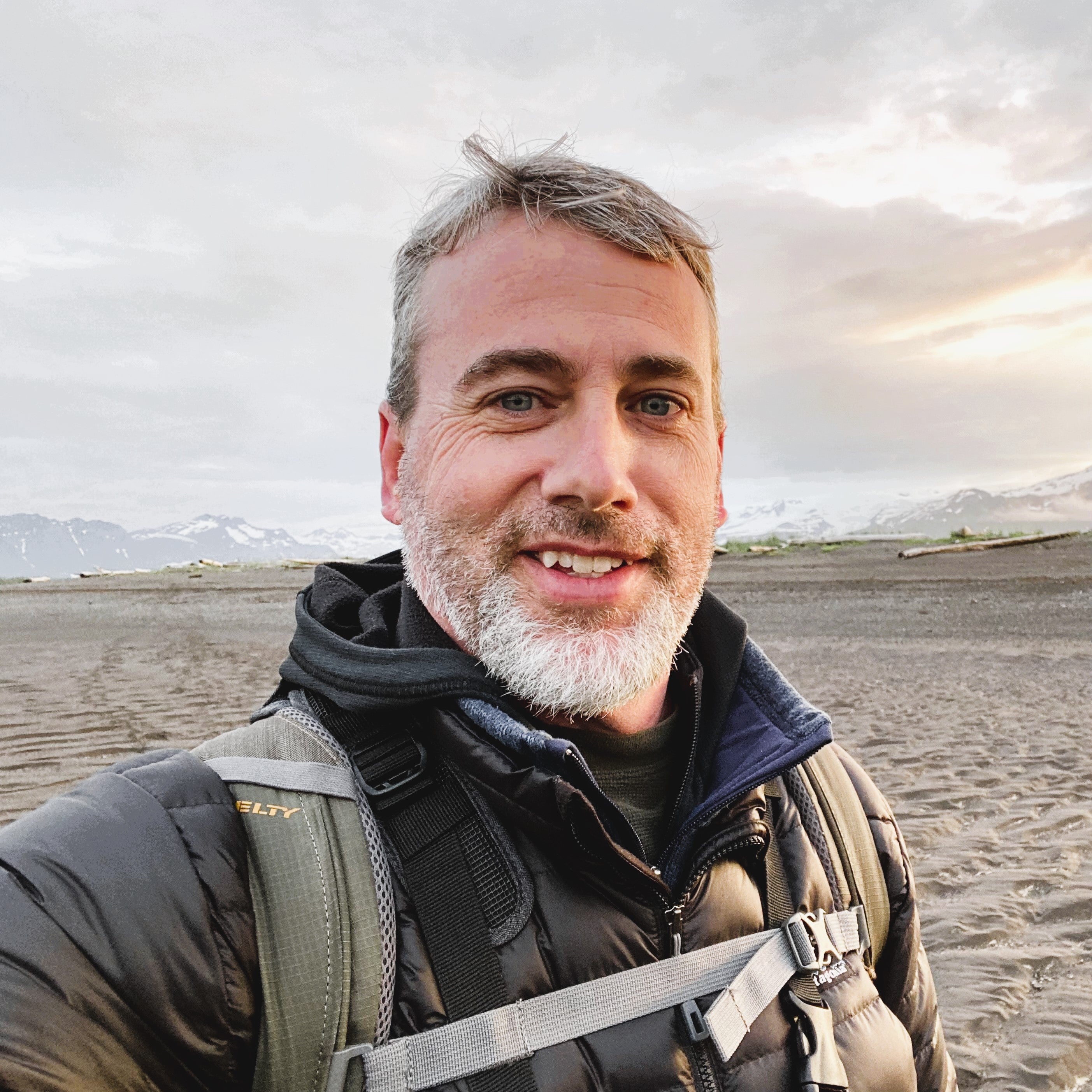 Man with beard who is apparently backpacking and looking at camera.