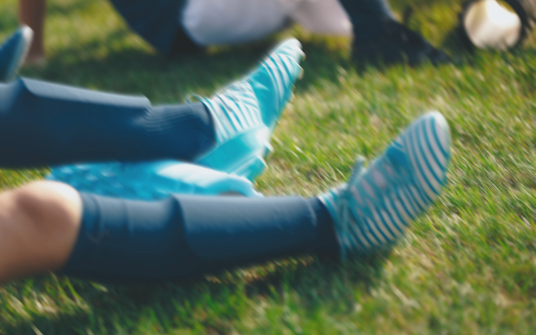 person with soccer cleats using a foam roller on their calf