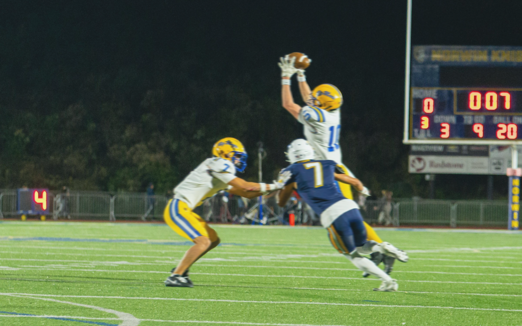 3 football players on the field catching a football