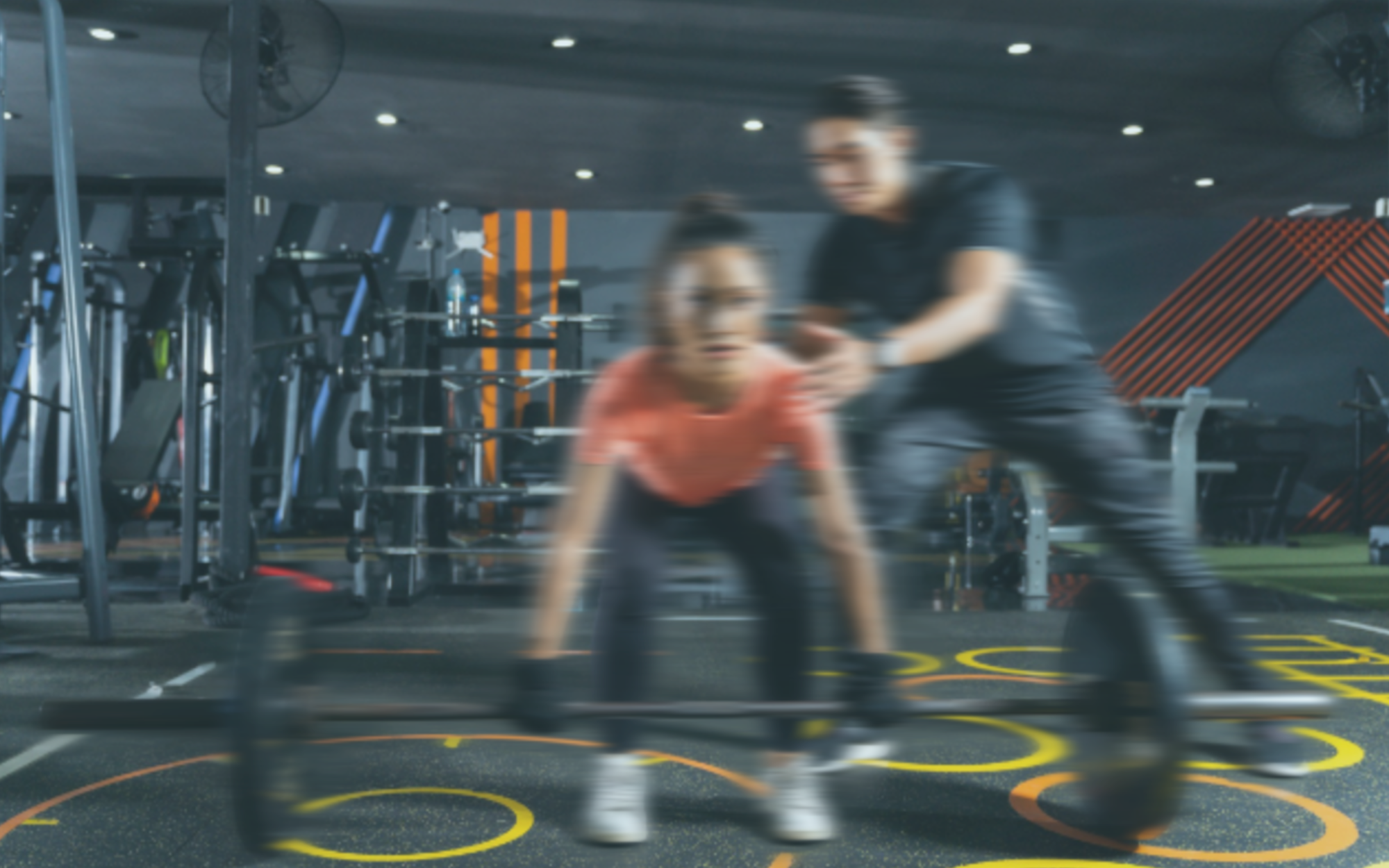 Two people working out with a barbell in a gym setting.