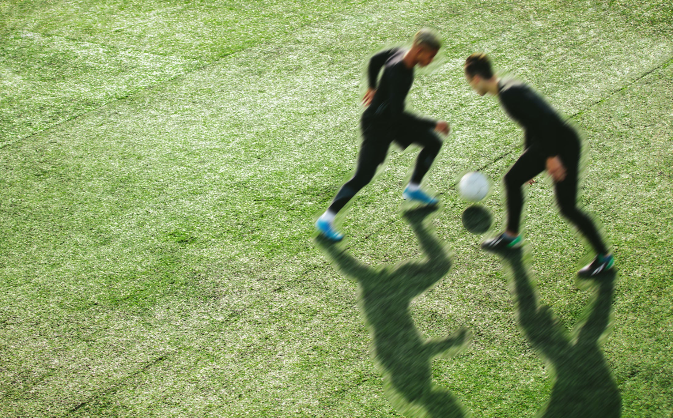 Two people playing soccer on a grass field