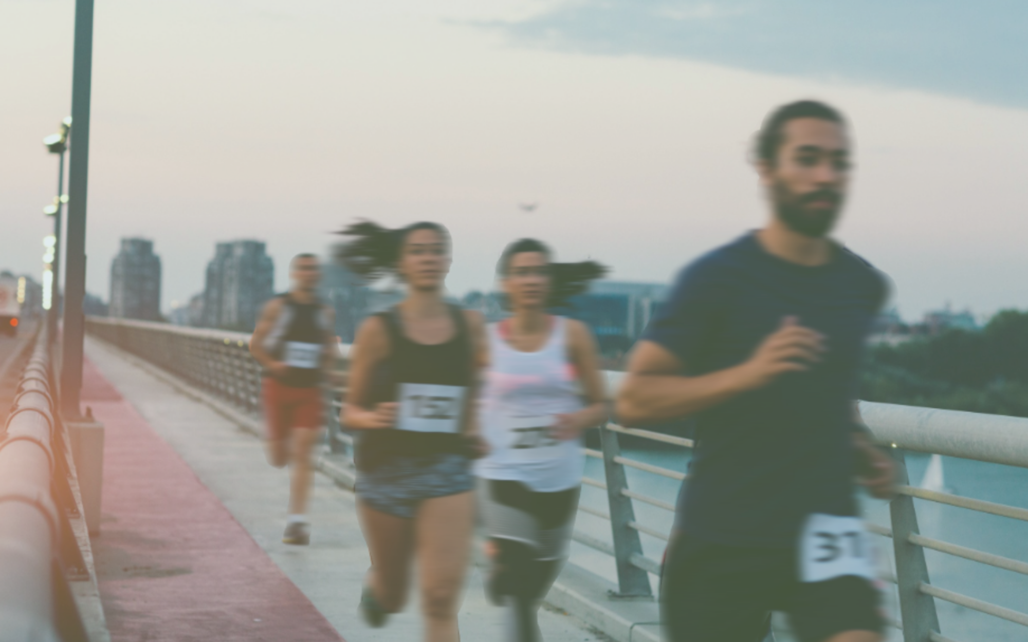Runners on a bridge with a city skyline in the background